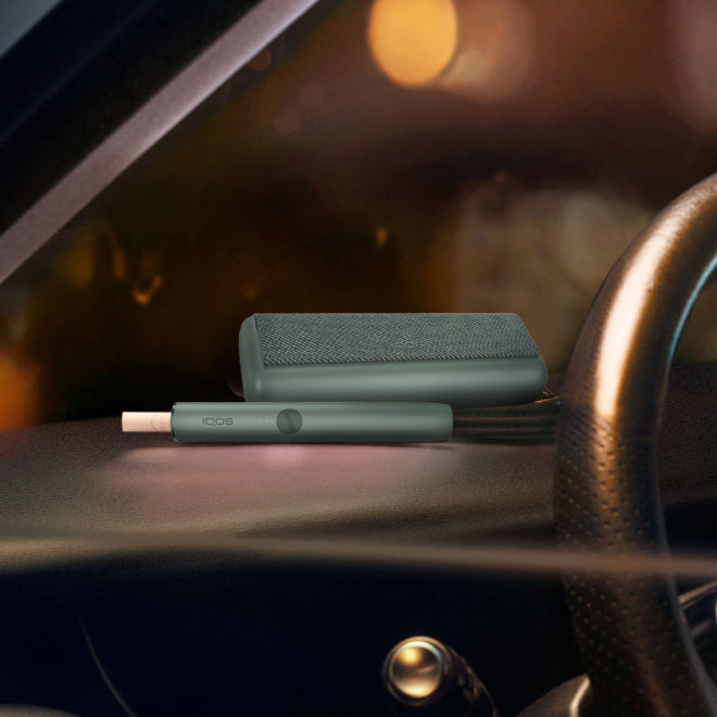An IQOS ILUMA PRIME Holder with a TEREA stick inserted next to an IQOS ILUMA Pocket Charger.