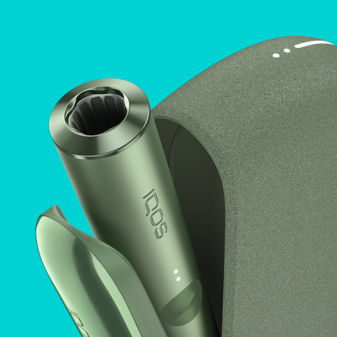 An IQOS ILUMA PRIME Holder with a TEREA stick inserted next to an IQOS ILUMA Pocket Charger.
