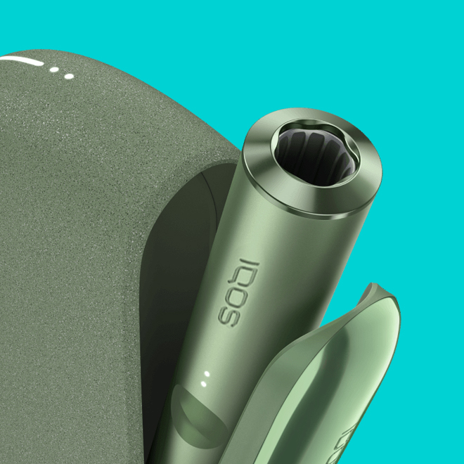 An IQOS ILUMA PRIME Holder with a TEREA stick inserted next to an IQOS ILUMA Pocket Charger.