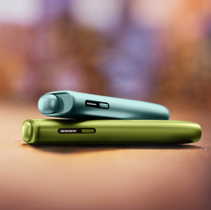 An IQOS ILUMA PRIME Holder with a TEREA stick inserted next to an IQOS ILUMA Pocket Charger.