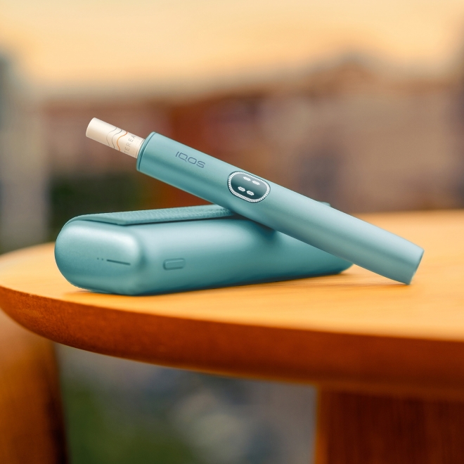 An IQOS ILUMA PRIME Holder with a TEREA stick inserted next to an IQOS ILUMA Pocket Charger.