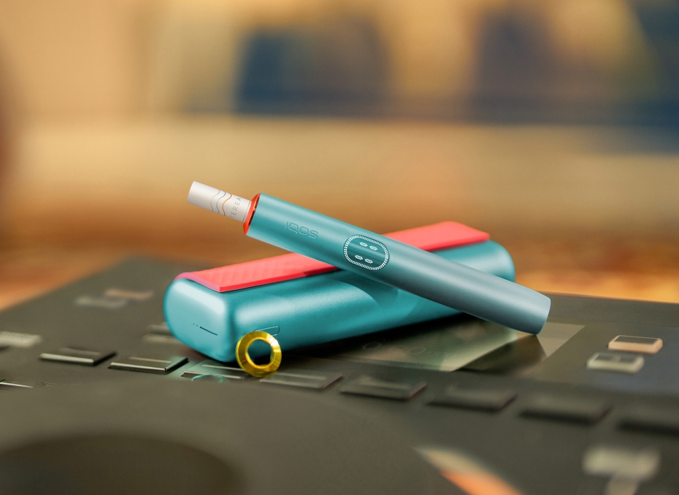 An IQOS ILUMA PRIME Holder with a TEREA stick inserted next to an IQOS ILUMA Pocket Charger.