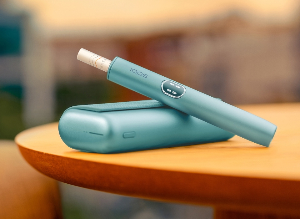 An IQOS ILUMA PRIME Holder with a TEREA stick inserted next to an IQOS ILUMA Pocket Charger.