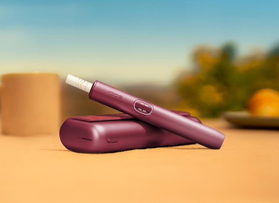 An IQOS ILUMA PRIME Holder with a TEREA stick inserted next to an IQOS ILUMA Pocket Charger.