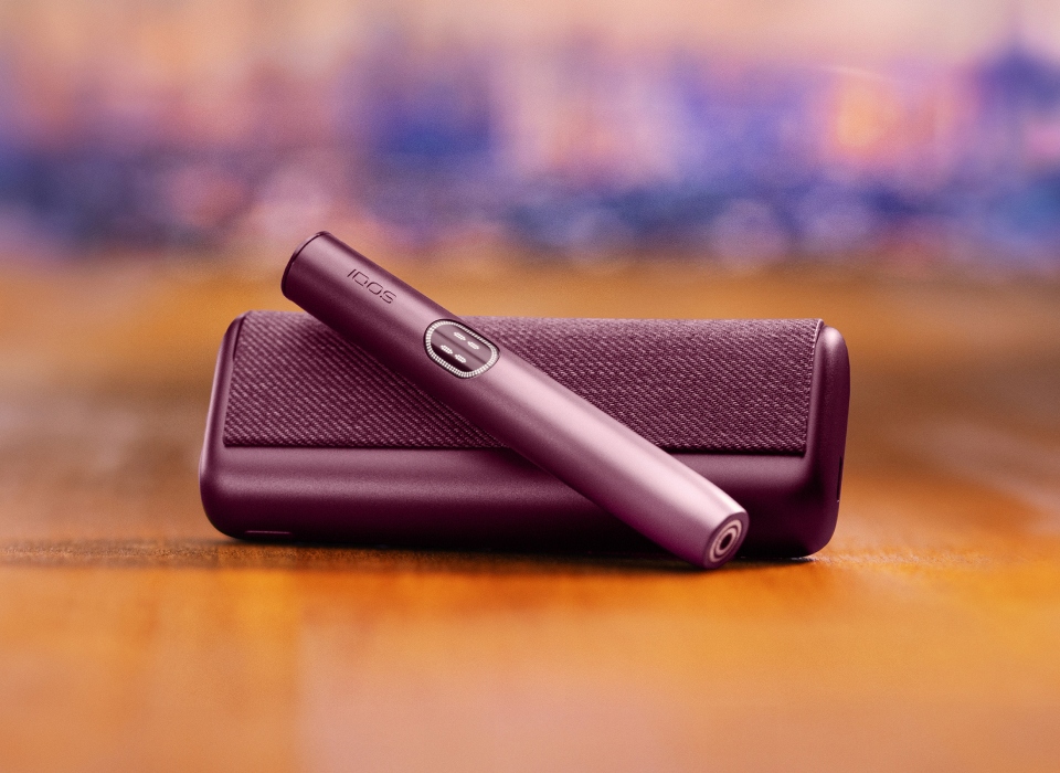 An IQOS ILUMA PRIME Holder with a TEREA stick inserted next to an IQOS ILUMA Pocket Charger.