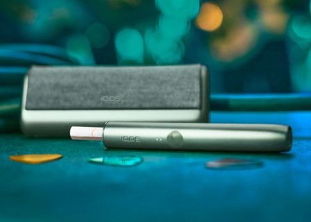 A jade green IQOS ILUMA holder and pocket charger.