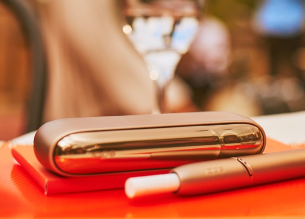 IQOS 3 DUO holder with HEETS stick and charger on a dinner table