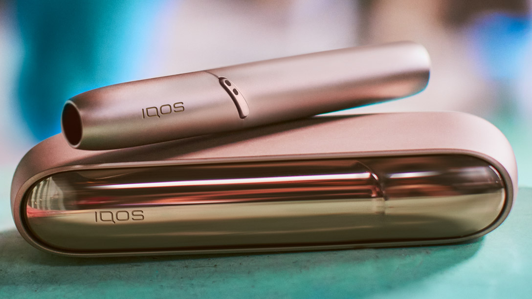 Blond woman opening her gold IQOS device
